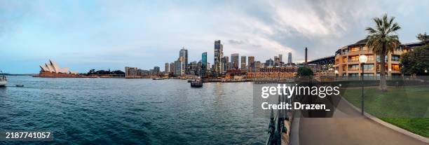 panoramic view of sydney harbour with the iconic sydney opera house and circular quay at sunset with city skyline in the background - circular quay stock pictures, royalty-free photos & images