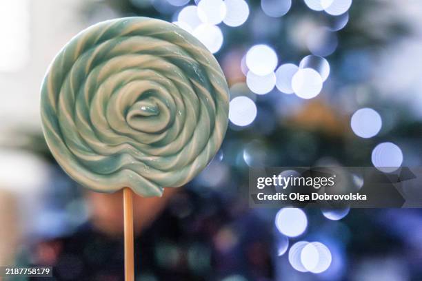 a close-up of a lollipop against a backdrop of lights - turquoise christmas ornaments stock pictures, royalty-free photos & images