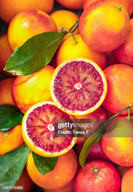 fresh blood oranges whole and halved with green leaves - blood orange peel stock pictures, royalty-free photos & images