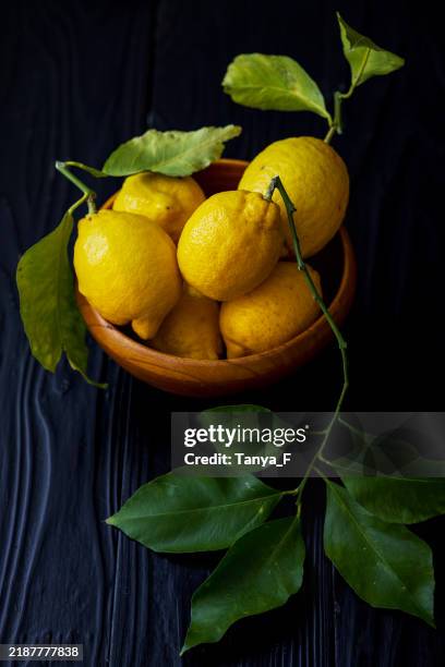 limoni freschi con foglie verdi su sfondo di legno scuro - albero di limone foto e immagini stock