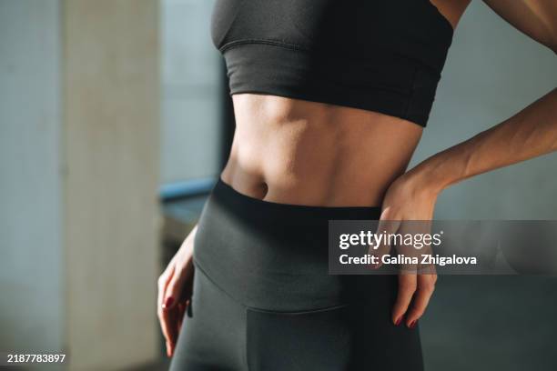 young slim woman in sportswear in modern studio. fitness girl with beautiful abdominal muscles - slim stock pictures, royalty-free photos & images