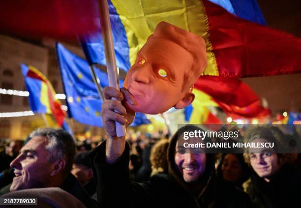 Man holds a 3D-printed mask of late dictator Nicolae Ceausescu as he takes part in a pro-European rally in support of democracy at Piata...