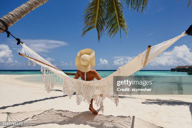 back view of a woman relaxing in hammock on the beach. - malediven stockfoto's en -beelden