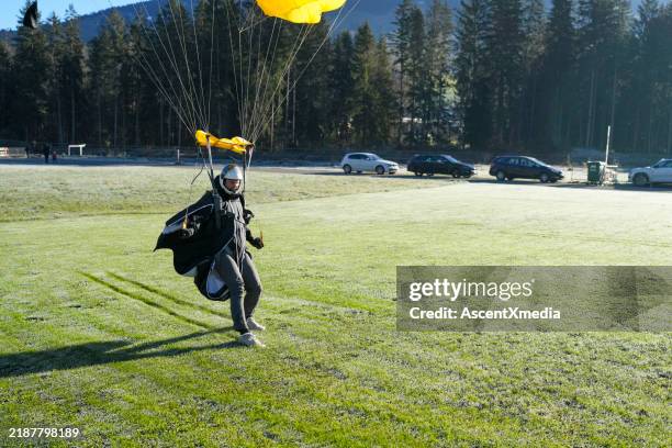 parasailer comes in for landing, through blue skies - parasailing stock pictures, royalty-free photos & images