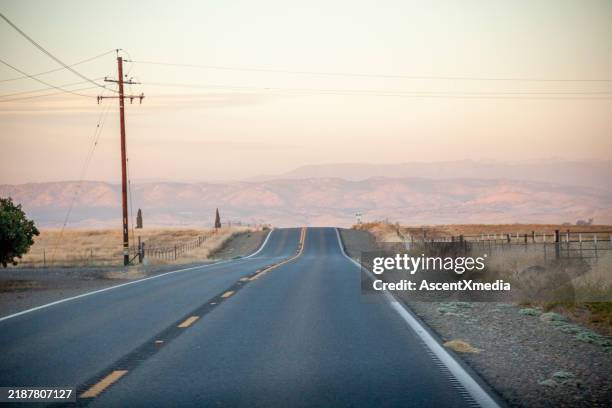 aerial view of rural road leading towards mountains - empty road stock pictures, royalty-free photos & images