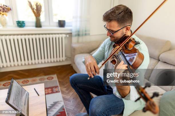 man practicing violin at home with music on tablet - violin stock pictures, royalty-free photos & images