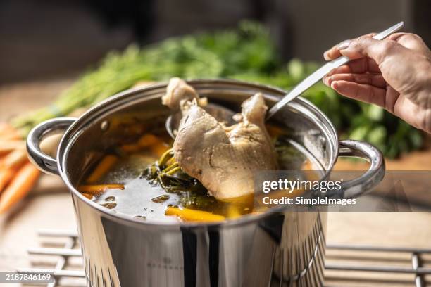the hands of a young cook take a cooked leg out of the chicken broth. - stew stock pictures, royalty-free photos & images
