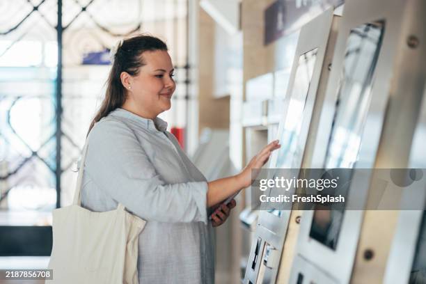 woman interacting with information kiosk in public space - digital signage stock pictures, royalty-free photos & images