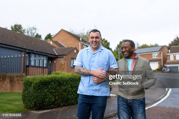 nurse and patient laughing together whilst walking outside - healthcare worker stock pictures, royalty-free photos & images