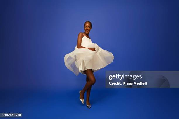 smiling young woman dancing in white dress - sleeveless dress stock pictures, royalty-free photos & images