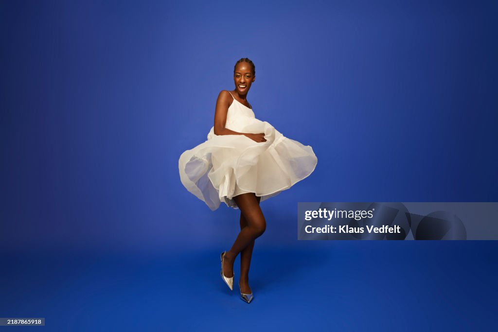 Smiling young woman dancing in white dress