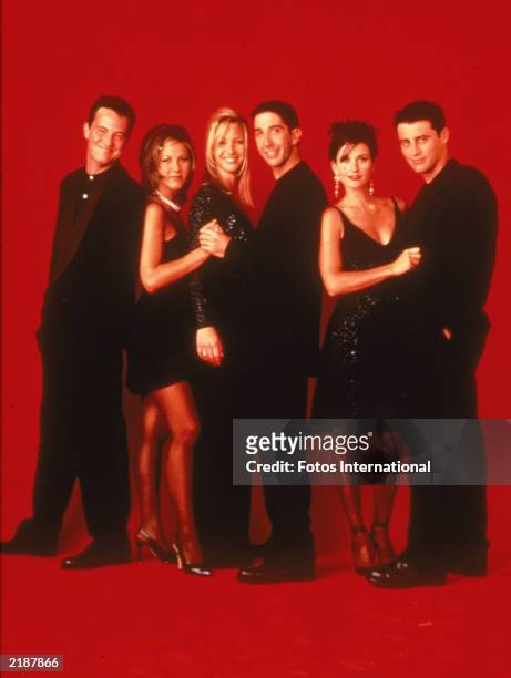 Promotional portait of the cast of the television series, 'Friends,' wearing black against a red backdrop, circa 1995. L-R: Matthew Perry, Jennifer...