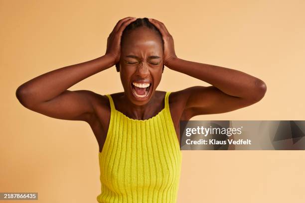 terrified young woman screaming with head in hands - kopf in den händen stock-fotos und bilder