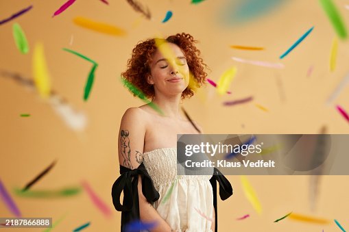 Smiling young redhead non-binary person amidst falling feathers Smiling young redhead non-binary person amidst falling feathers