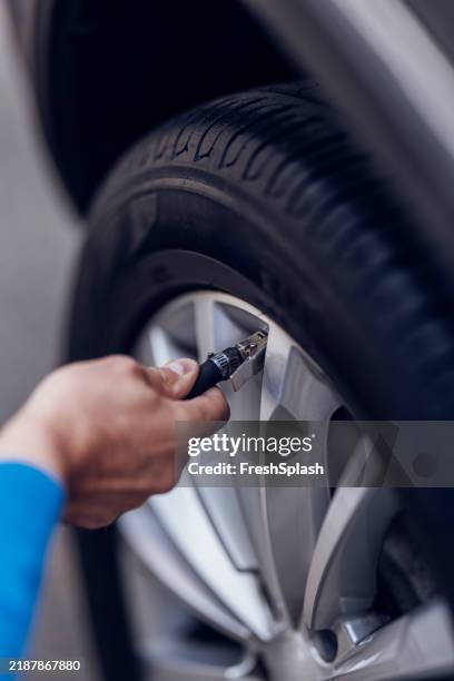 gros plan de la main vérifiant la pression des pneus de voiture avec la jauge - manomètre de pression photos et images de collection