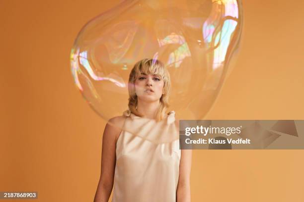 confident young blond non-binary person looking through bubble - giant bubble stock pictures, royalty-free photos & images