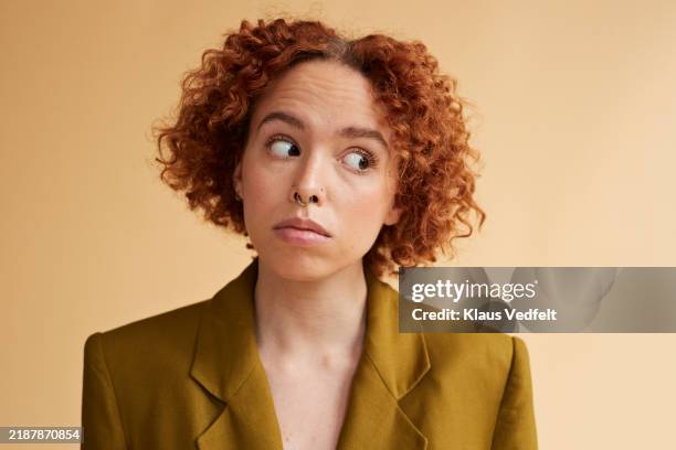 confident redhead non-binary person looking sideways - irritación fotografías e imágenes de stock
