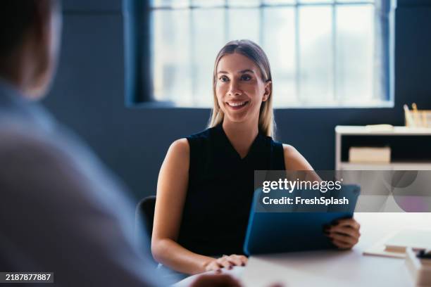 confident businesswoman holding tablet in a modern office setting - blonde guy stock pictures, royalty-free photos & images