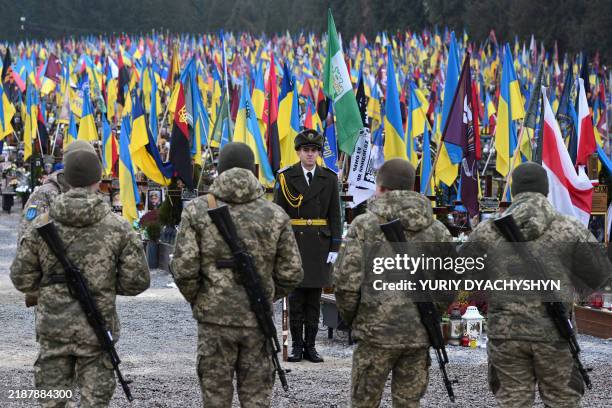 Ukrainian servicemen pay tribute to fallen Ukrainian soldiers at the Lychakiv cemetery on the Day of the Armed Forces of Ukraine, in Lviv on December...