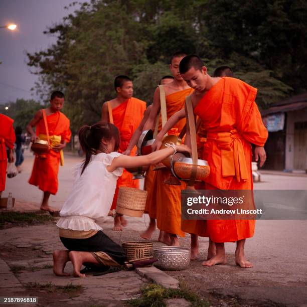 scena di strada mattutina con monaci a luang prabang, laos - elemosina oggetto religioso foto e immagini stock