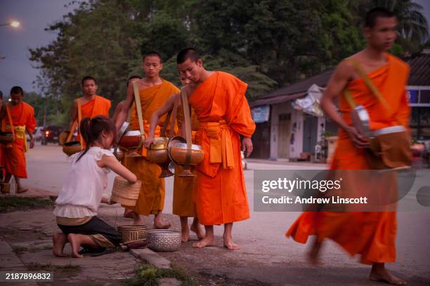 scena di strada mattutina con monaci a luang prabang, laos - elemosina oggetto religioso foto e immagini stock