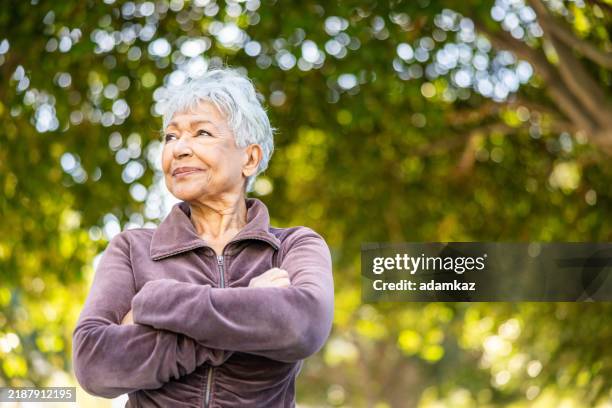 mixed race senior woman stretching with weights working out outdoors - senior women stock pictures, royalty-free photos & images