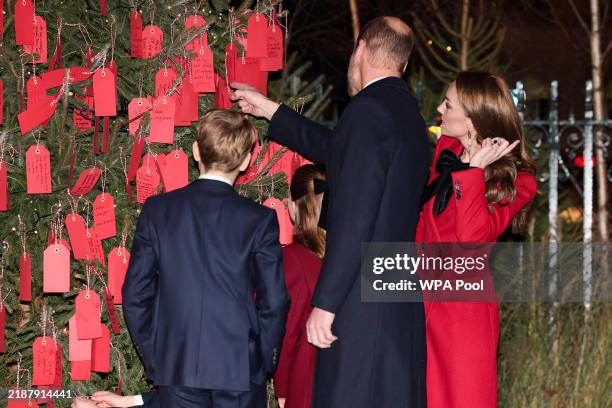 Britain's Prince William, Prince of Wales, points at a written message next to Catherine, Princess of Wales, Prince George, and Princess Charlotte as...