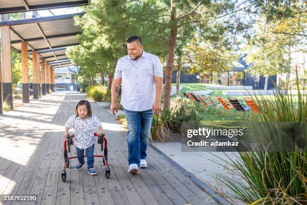 niño hispano con el síndrome de down con walker de papá - discapacidad del desarrollo fotografías e imágenes de stock