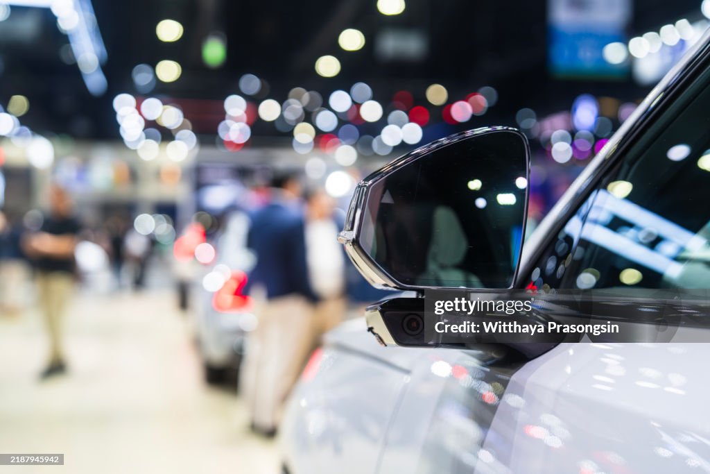 Close-Up of Car Mirror at a Vibrant Auto Show with Bokeh Effect