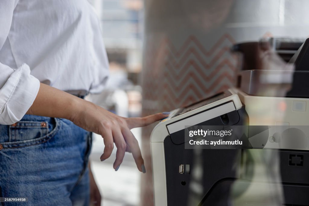 Businesswoman's Hand Pressing the Copy Machine Button in a Modern Office, Reflections in the Window