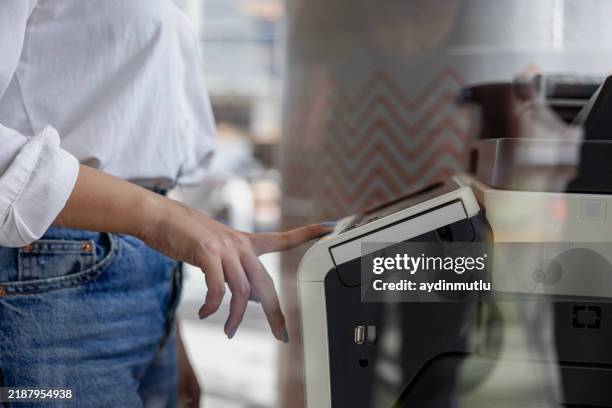 businesswoman's hand pressing the copy machine button in a modern office, reflections in the window - computer printer stock pictures, royalty-free photos & images