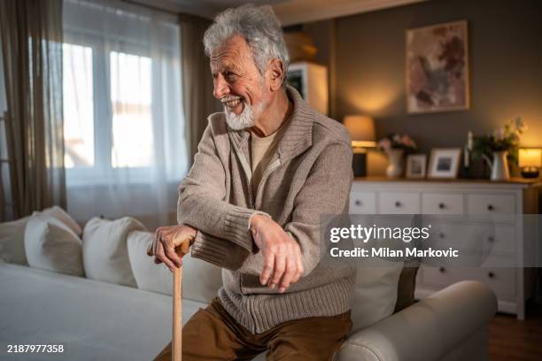 in a quiet moment, an elderly man with a cane sits in the living room - parkinsons disease stock pictures, royalty-free photos & images