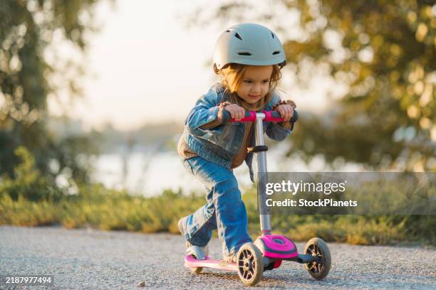girl driving push scooter in park - trotinete imagens e fotografias de stock