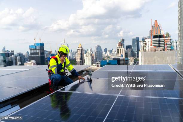 engineer inspects solar panels on rooftop against urban skyline - energy transition stock pictures, royalty-free photos & images