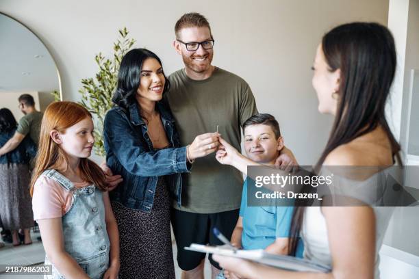 multiethnic family with two children buying new house. real estate agent handing over the keys to satisfied family. - house key stock pictures, royalty-free photos & images