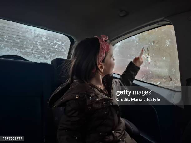 un niño dibuja en la ventanilla del coche durante un día de invierno - tomado desde un teléfono móvil fotografías e imágenes de stock