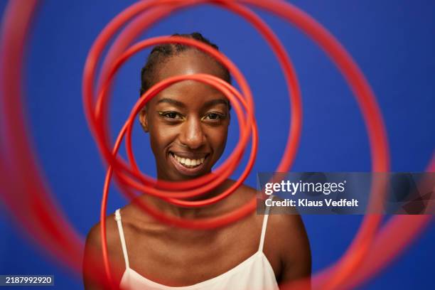 smiling young woman looking through spiral red cable - circle circumference stock pictures, royalty-free photos & images