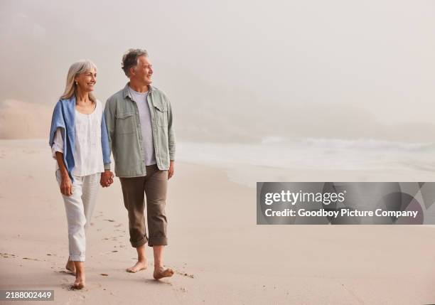 casal sênior afetuoso andando e de mãos dadas na praia - 65 69 anos - fotografias e filmes do acervo