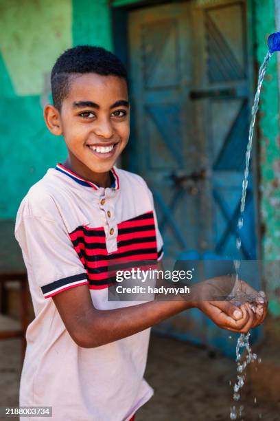 african young boy drinking fresh water, east africa - ethiopian ethnicity stock pictures, royalty-free photos & images