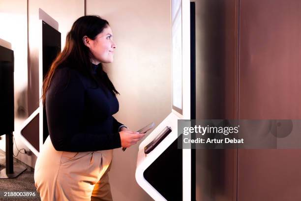 woman paying contactless with smartphone in a self service kiosk at the cinema - interactivity stock pictures, royalty-free photos & images