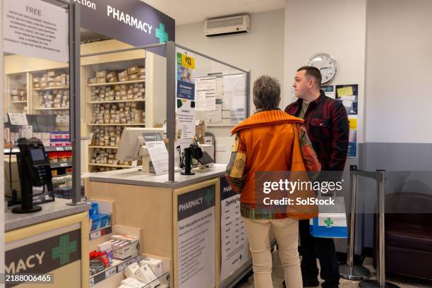 grandson assisting grandmother at the pharmacy - chemist stock pictures, royalty-free photos & images