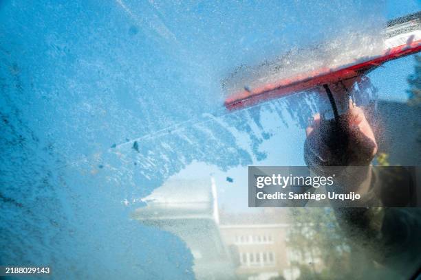 cleaning ice from a car windshield seen from the inside - quitahielo fotografías e imágenes de stock
