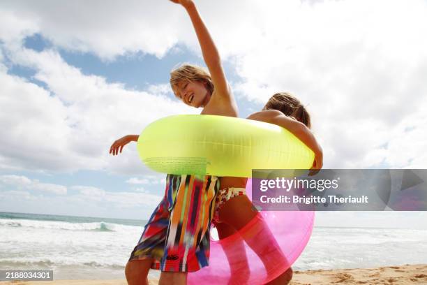 young siblings playing with flotation devices on hawaiian beach - hawaii sun tan stock pictures, royalty-free photos & images