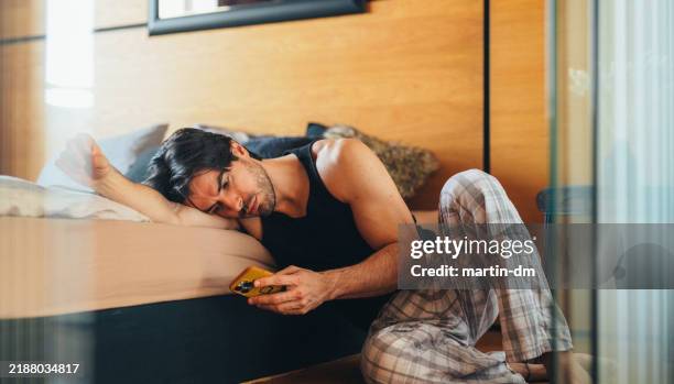 uomo nella sua camera da letto mentre naviga in rete - cuore spezzato foto e immagini stock