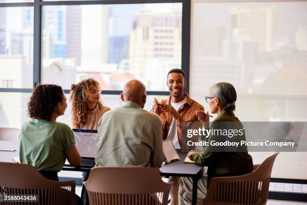 cheerful mid adult man smiling and talking to four business colleagues in meeting - day in the life series stock pictures, royalty-free photos & images