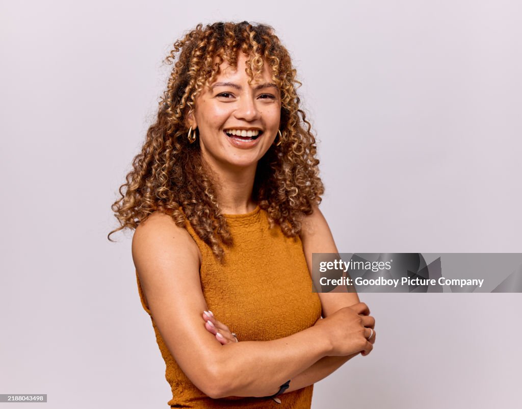 Studio portrait of cheerful young woman with arms folded, smiling