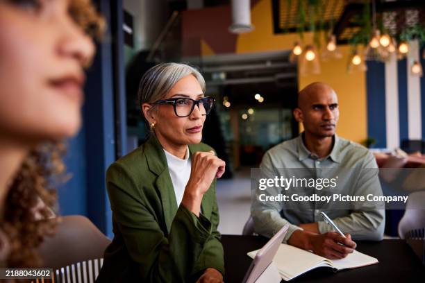 confident female manager wearing glasses listening carefully in team meeting - een dag uit het leven serie stockfoto's en -beelden