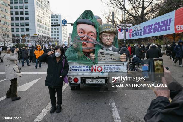 Woman poses with effigies of South Korean President Yoon Suk Yeol and US president-elect Donald Trump during a protest calling for the ouster of...