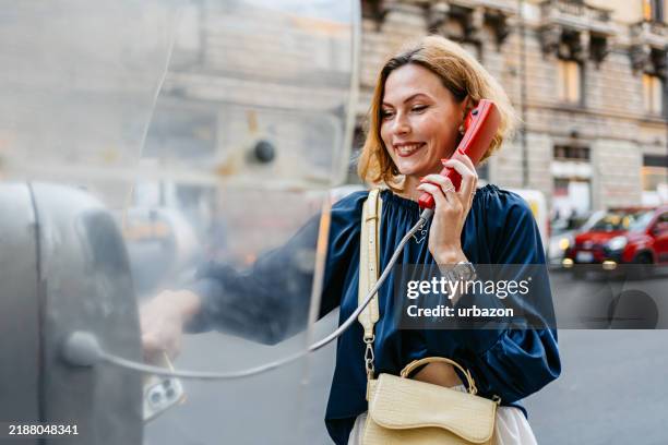 mid-adult woman talking on the payphone on the street in palermo in italy - pay phone stock pictures, royalty-free photos & images