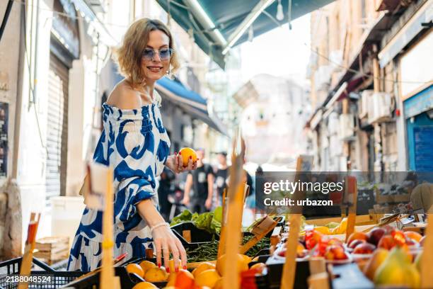 mid-adult woman shopping for oranges at the street market in palermo in italy - mezzogiorno stockfoto's en -beelden